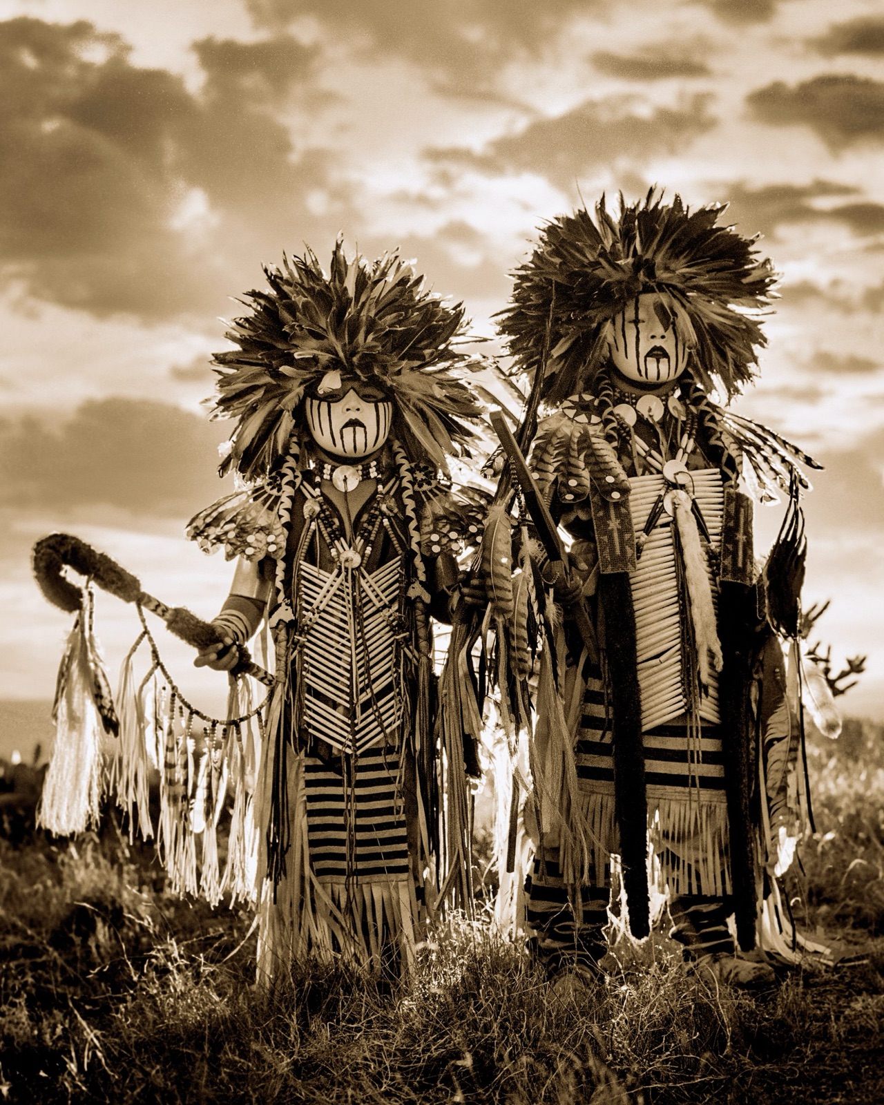 Two dancers in full feathered regalia and face paint