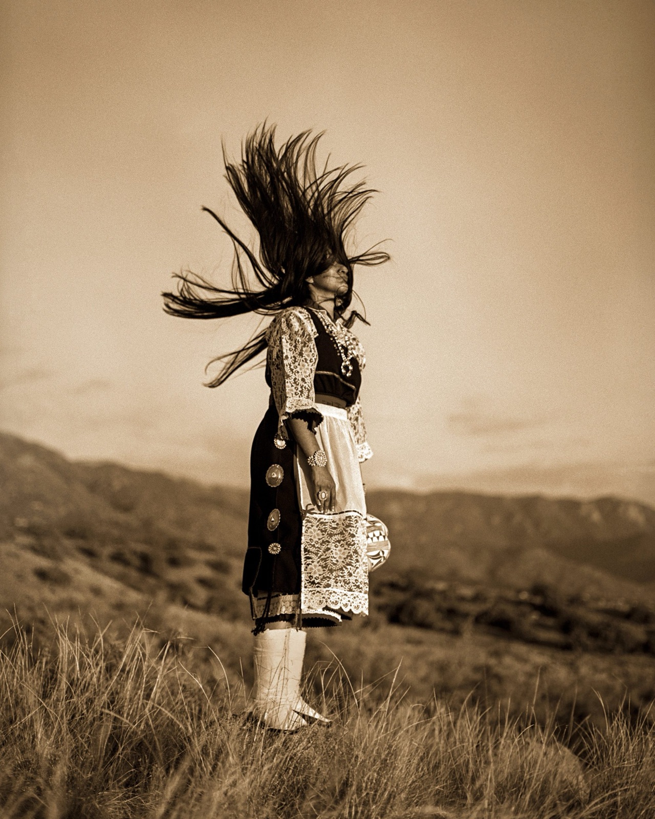A woman on a ridgeline, hair swept upward by the wind