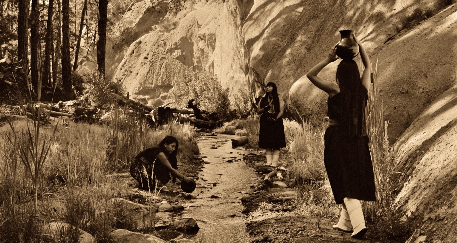 Three young girls beside a stream and rock face